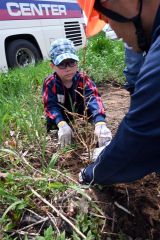 森林組合の職員にアドバイスをもらって町有林にカラマツの苗木を植樹する児童