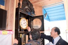 参加者に大時計の分銅の巻き上げを教える吉田さん（右）