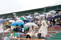 雨の中、第１試合の開始を待つ足寄町民ら