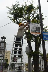 通り沿いの街路灯にフラッグを設置する長谷理事長