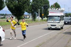 平和の火のたいまつを手に町内を走るランナー