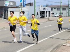 平和の火のたいまつを手に町内を走るランナー