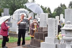 雨が降る中、傘を差して墓参りする参拝者（１３日午前１０時ごろ、帯広市内の緑ケ丘墓地で）