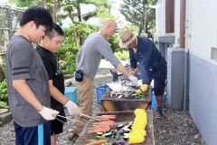 野菜やフランクフルトを焼く参加者