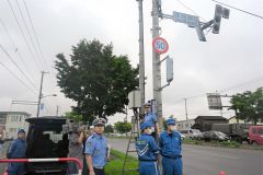 信号機横に止めたＨＶ（左）を電源に復旧の操作手順を確認する署員