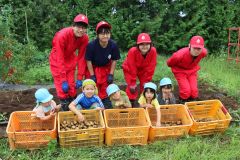 収穫したジャガイモを手に笑顔の園児と士幌高生