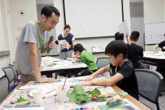小寺さん（左）にアドバイスをもらって葉っぱアートづくりをする参加者