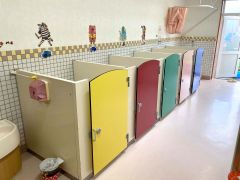 保育園のトイレはカラフルで、壁には園児の好きな乗り物やキャラクターが貼られ楽しい雰囲気がある
