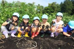 掘ったジャガイモを手にする園児たち