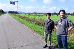 広尾町の農村風景をバックにフットパスのコースを検討している磯野さん（写真右。左は協力隊インターンの佐藤さん）