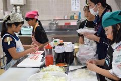 夕食を作る児童と手助けする池田高校の生徒や学習支援ボランティア