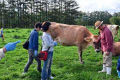 橋本さん（右）の放牧地で牛を見学する参加者