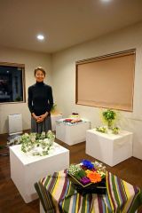 カフェ内で開かれている作品展と吉田さん。個性あふれる作品が並ぶ