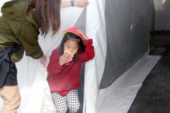 訓練用の煙が充満したテントから避難訓練する子どもたち
