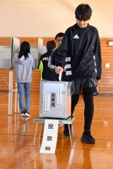 投票箱に一票を投じる児童