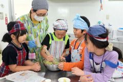 浦木さん（左から２人目）とスイートポテト作りに挑戦する児童ら