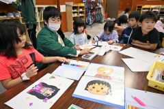学童保育の児童を前に、アニメのキャラクターなどを書き上げる野田あかりさん（左から２人目）
