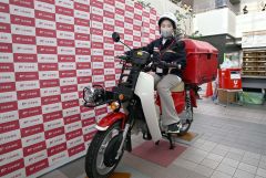 郵便局員にふんしバイクにまたがる子ども（須貝拓也撮影）