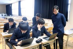 佐藤さん（前列右）、吉本さん（後列右）から試作品の観光パンフをパソコンの画面で見せてもらう生徒ら