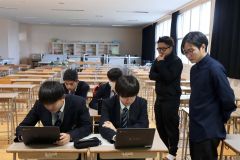 佐藤さん（前列右）、吉本さん（後列右）から試作品の観光パンフをパソコンの画面で見せてもらう生徒ら