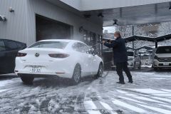 洗車機を使ってレンタカーの雪を取り除く男性（２８日午前７時４０分ごろ、ＪＲ帯広駅前）