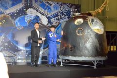 ソユーズの帰還カプセルを披露する前沢さん（右）。カプセルの表面は焼け焦げていた