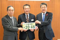 十勝ナンバーのデザイン画を手にする（左から）竹中会長、芳賀局長、浜田正利副会長