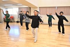原田さん（中央）の指導の下、ゆっくりとした太極拳の動きで心身の健康を目指す会員たち