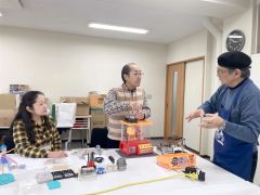 高橋さん（右端）の助言を受けながらおもちゃを“診察”する富士田さん（中央）ら