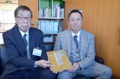 安田氏から寄贈された「十勝鮭鱒人工孵化場事業成績」を掲げる（右から）中村組合長と菅原副町長