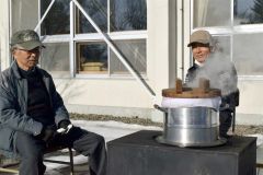 保存会の持つまきストーブでもち米を蒸す小原会長（左）と事務局の中村さん
