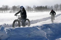 風が強く雪が舞う中で雪上ファットバイクを体験する参加者
