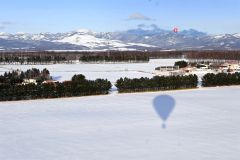 搭乗する気球の影がくっきりと雪原に浮かび上がる。奥は上士幌高の気球