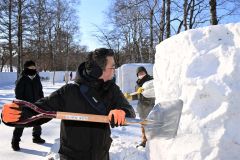 スコップで雪の塊を削りながら氷像を造る参加者（２０日午前１０時１５分ごろ、須貝拓也撮影）