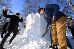 雪の塊を削り氷雪像を造る参加者（２０日午前１０時１５分ごろ、須貝拓也撮影）
