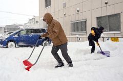 駐車場の除雪に追われる市民（２３日午前８時ごろ、須貝拓也撮影）