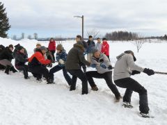 雪上で力一杯綱を引く参加者たち