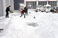 除雪に追われる帯広日産ドーム店の従業員（１６日、午前９時ごろ、市内西７南２０で。金野和彦撮影）