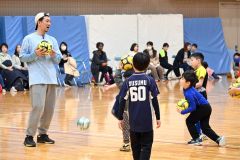 曽田会長（左）に教わりながらサッカーをする児童たち