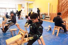 「削り馬」にまたがり、椅子の脚の製作に熱中する児童