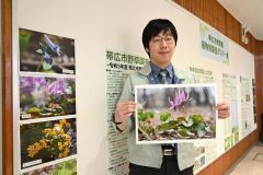 カタクリの花の写真を持ち、野草園への来園を呼びかける須賀さん