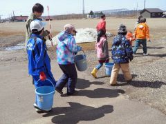 小学校から放流場所まで、稚魚が入ったバケツを運ぶ児童ら