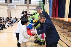 レバンガと北海道クボタからバスケットボールとビブスを受け取る児童たち