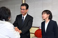 支持者と握手を交わす田中氏。右は妻朋子さん（２１日、午後９時４０分ごろ、広尾町内の選挙事務所で。金野和彦撮影）