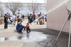 消防隊員（左）と放水体験をする子ども