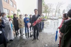 役場玄関前で職員や町民の歓迎を受ける田中新町長（３０日午前８時３５分、石原秀樹通信員撮影）