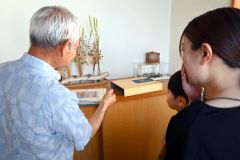 山下さん親子に国連切手を見せる澤田さん（左）