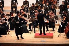 迫力の演奏を聴かせた帯広交響楽団のメンバーとバイオリニストの成田さん。指揮は澤村さん