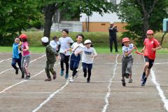 ３・４年生のリレーで力いっぱい走り、次の仲間にバトンを渡す子どもたち（８日、更別小学校。金野和彦撮影）