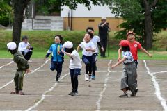 ３・４年生のリレーで力いっぱい走り、次の仲間にバトンを渡す子どもたち（８日、更別小学校。金野和彦撮影）